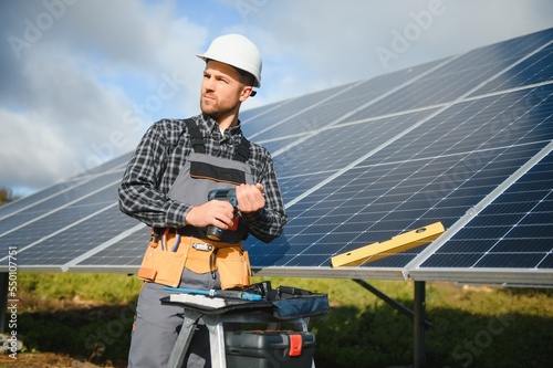 Professional worker installing solar panels on the metal construction, using different equipment, wearing helmet. Innovative solution for energy solving. Use renewable resources. Green energy.