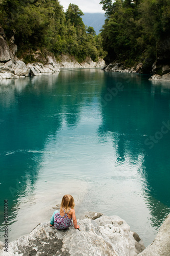 A young girl looks out over the turquoise water of the Hokitika River in the Hokitka Gorge, New Zealand. photo