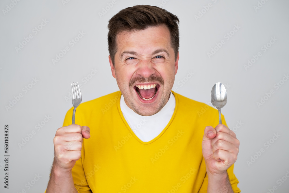 handsome hungry young man holding fork and spoon waiting for dinner handsome hungry young man holding fork and spoon waiting for dinner