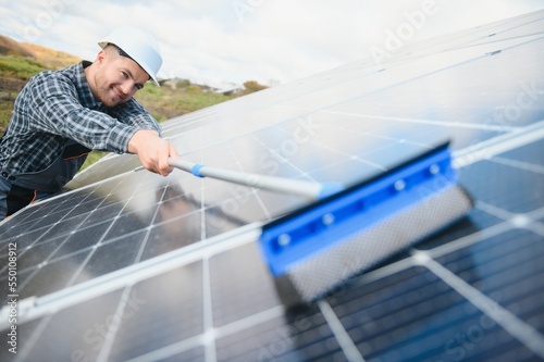 A worker cleaning dust and dirt form solar panels. © Serhii