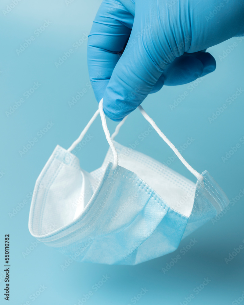 Fototapeta premium Medical protective mask on a blue background, coronavirus prevention, virus protection factor. Medical or surgical face mask. Virus protection. Respiratory respiratory mask.