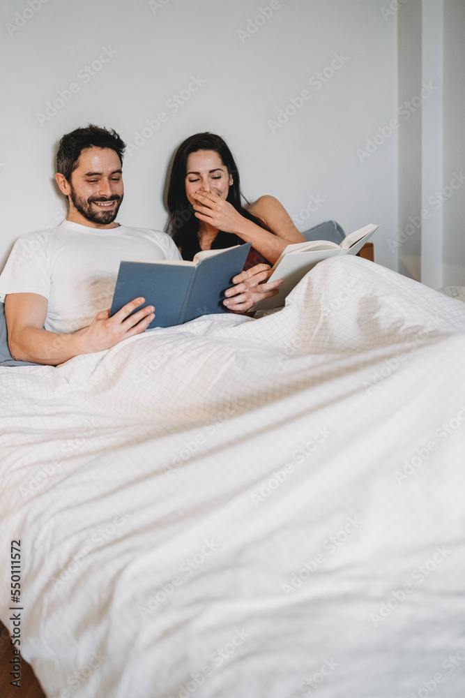 Loving couple reading under covers in bed at home in a moment of rest Loving couple reading under covers in bed at home in a moment of rest