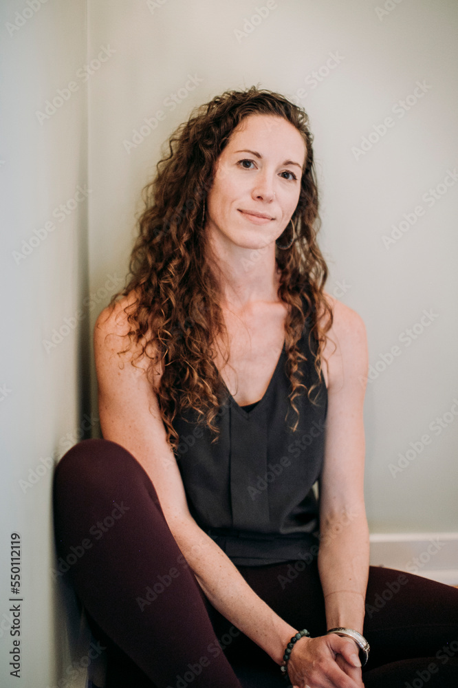 portrait of middle age fit woman against white wall in corner of room portrait of middle age fit woman against white wall in corner of room