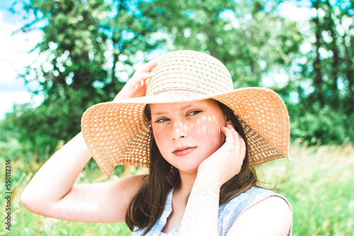 Girl in a Green Field Wearing a Floppy Sun Hat on a Bright Summer Day photo