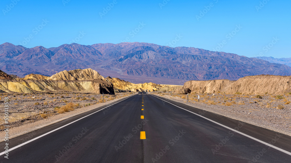 Desert Road - A wide angle view of newly resurfaced highway 190, extending towards rugged purple Panamint Range, at side of Zabriskie Point on a sunny Winter day, Death Valley National Park, CA, USA.