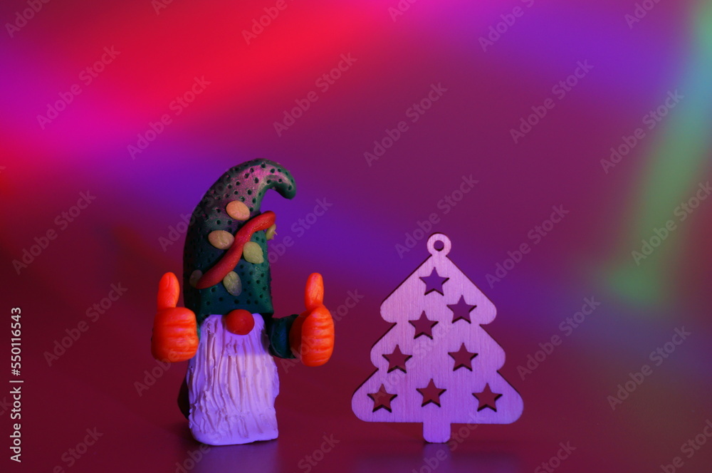 A figure of a joyful gnome and a Christmas tree on a colored background. Bright colored background. A festive event. A New Year's character.