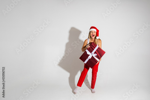 handsome woman with red and white christmas hat holds a big box with present and rejoices photo