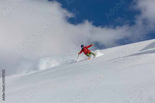 A skier in a red suit makes a sharp turn on a freeride downhill
