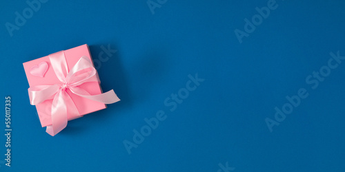 Pink gift box with pink bow on dark blue background. Valentine day, 8th march, Mothers day background. Flat lay, top view, copy space