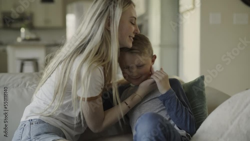 Slow motion of girl on sofa kissing little brother on cheek / Highland, Utah, United States