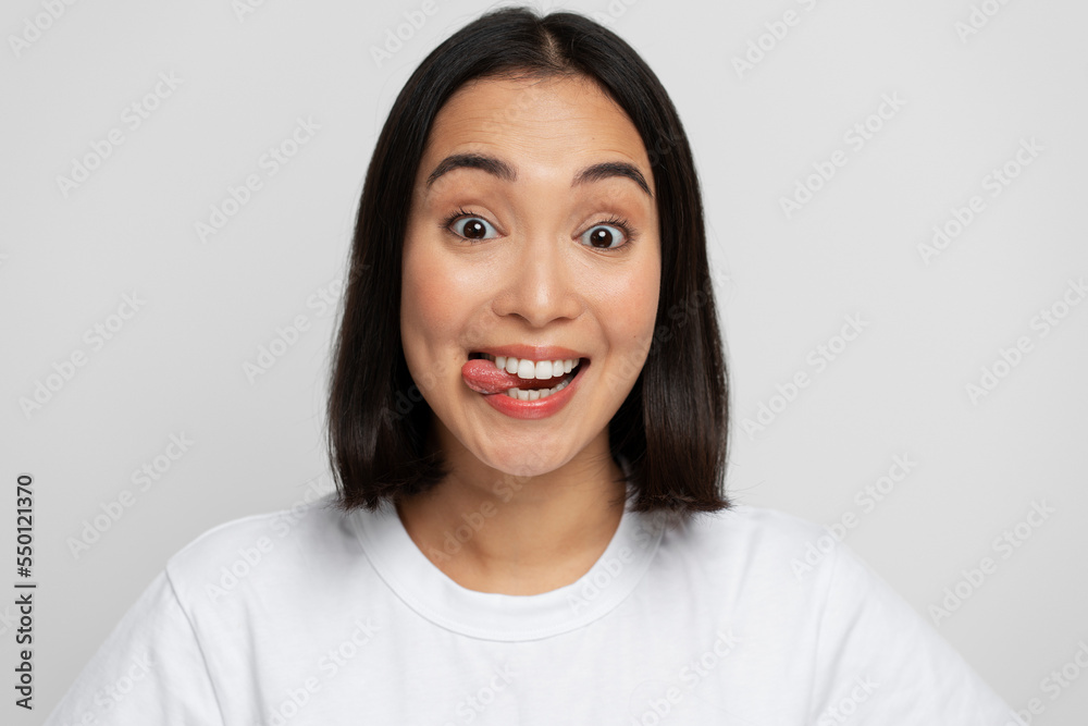 Portrait of positive playful woman standing with tongue out, demonstrating childish behaviour Portrait of positive playful woman standing with tongue out, demonstrating childish behaviour