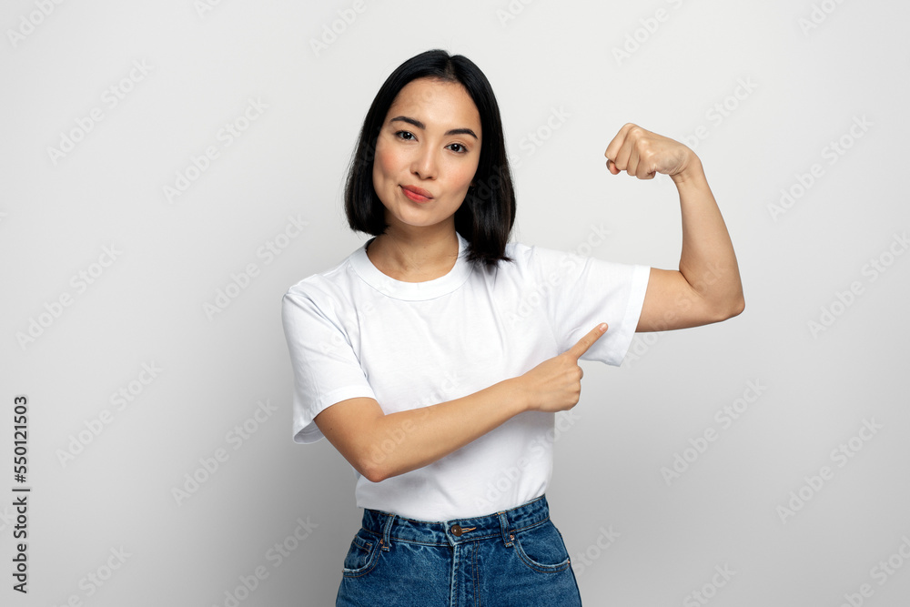 Woman raising arms showing biceps as metaphor of female power and independence Woman raising arms showing biceps as metaphor of female power and independence