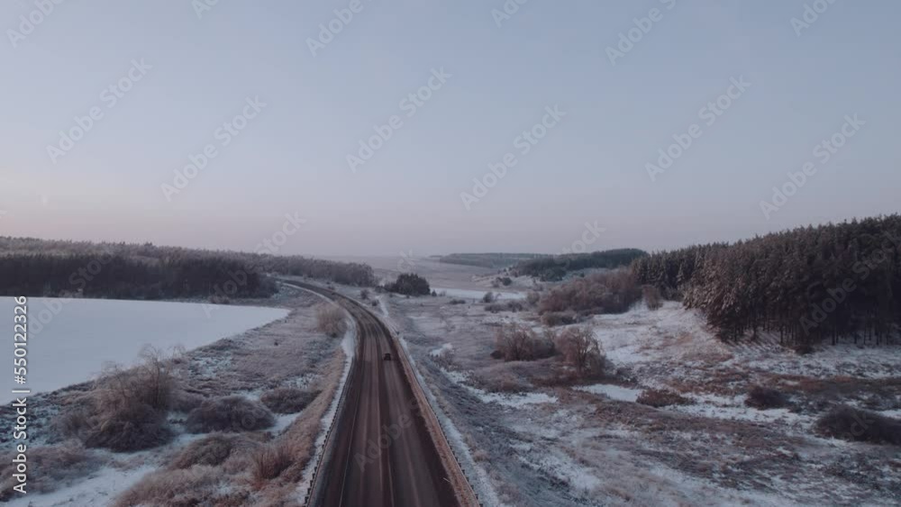 Aerial photography of the highway in winter along the forest at sunset, car traffic in winter. Aerial photography of the highway in winter along the forest at sunset, car traffic in winter.