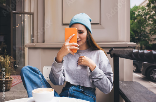 Young millennial female using social network application on mobile phone for communication. Caucasian hipster girl holding smartphone in silicone case. Teenager browsing online with internet data photo
