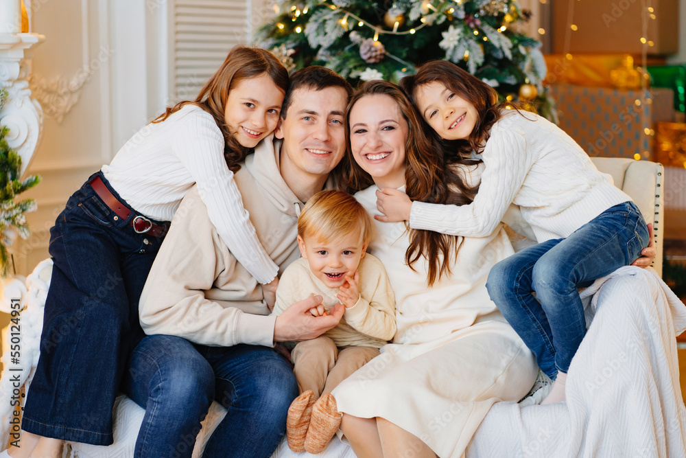 Beautiful happy large family on the couch by the Christmas tree.