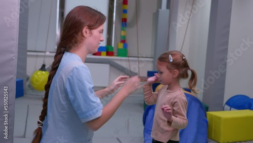 Child girl give five physiotherapist during sensory integration session. The concept of happiness and one team together. Cheerful kid and therapist celebrating teamwork at lesson.