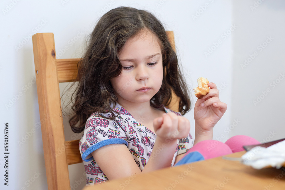 pretty girl eating toast with butter at the kitchen table for breakfast pretty girl eating toast with butter at the kitchen table for breakfast