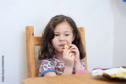 pretty girl eating toast with butter at the kitchen table for breakfast