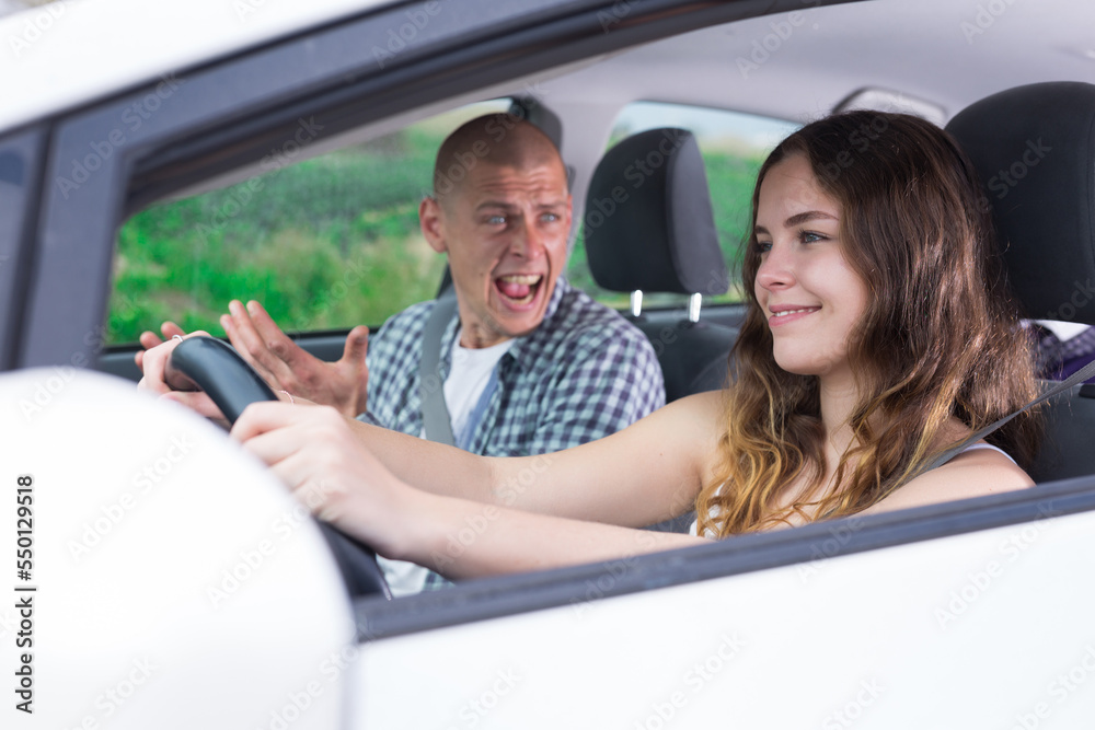 Young attractive girl driving car with man in passenger seat during trip, side view