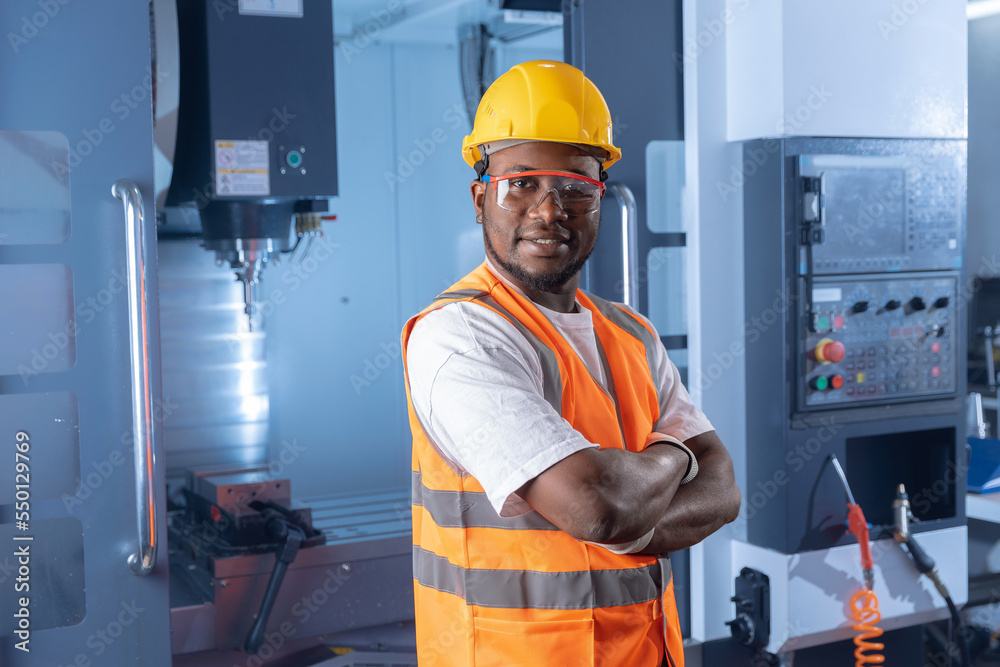 Portrait professional african american engineer man in helmet uniform background CNC machinery, blue toning. Concept industry factory people Portrait professional african american engineer man in helmet uniform background CNC machinery, blue toning. Concept industry factory people
