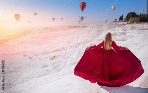 Young Woman in red dress background Pamukkale Hot air balloon flying Travertine pool and terraces sunset. Concept Travel Turkey