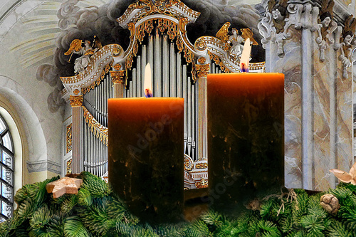 Zwei brennende Adventskerzen vor einer großen Kirchorgel. Zweiter Advent