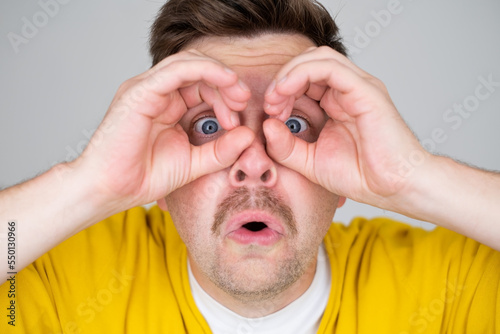 Caucasiann man making binoculars shape with his hands and looking through it  photo