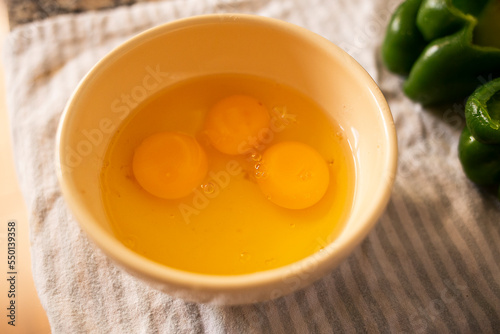 egg whites and yolks seasoned inside a ceramic container on a wood