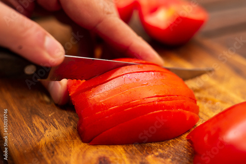 person cutting tomatoes in julienne on a wood