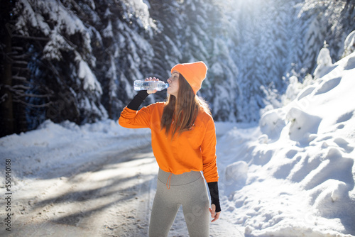 Female runner drinking water at winter day