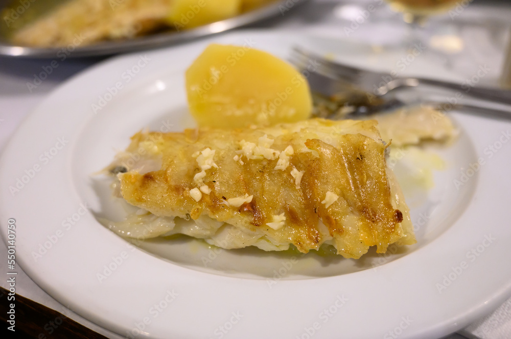 Grilled fillet of white codfish served with potatos in fish restaurant in Portugal