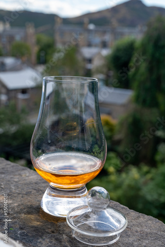 Glass of single malt scotch whisky served on old window sill in Scottisch house with view on old part of Edinburgh, Scotland, UK © barmalini