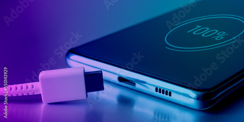 Fotografi Fully charged battery icon on the touch screen of the cell phone and a USB Type-C cable