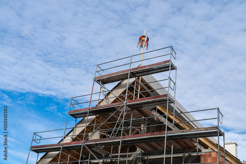 Unfinished house with scaffolding and typical greman may pole or maibaum on the roof. Unfinished house with scaffolding and typical greman may pole or maibaum on the roof.