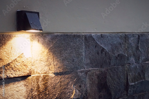 A yellow light bulb that mounted on stone and concrete wall for vintage or abstract background