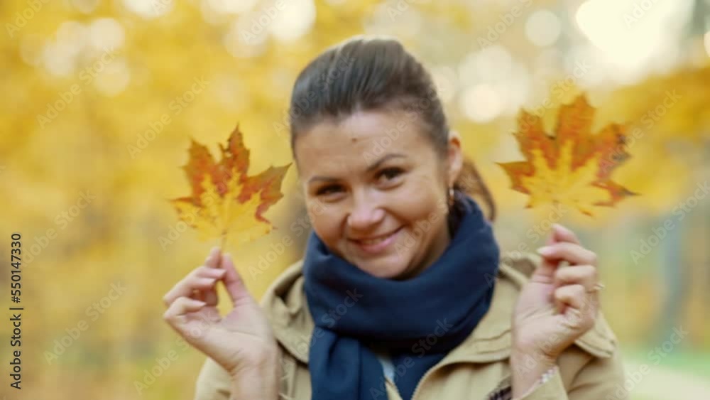 Portrait of a happy girl making funny faces covered with autumn leaves.