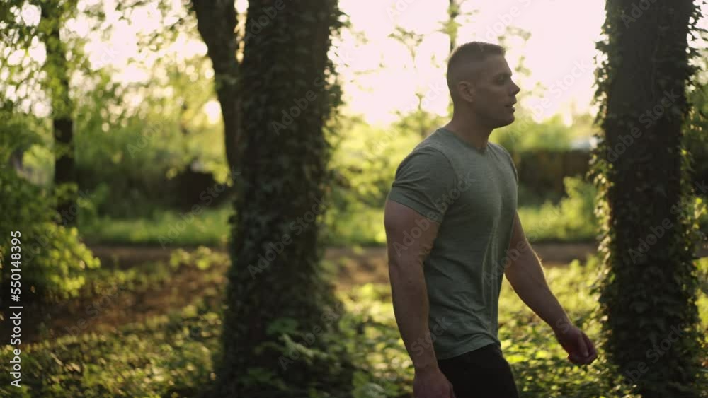 Young athletic man walking and resting after a workout in the forest. Healthy lifestyle concept. Slow motion.