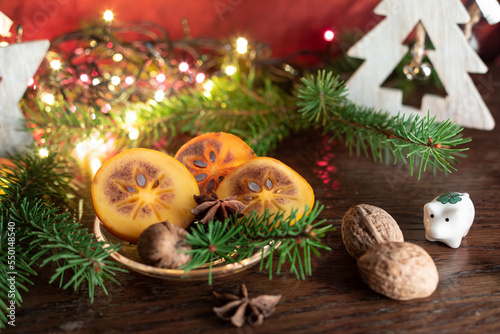 New Year or Christmas decoration with wooden star slices of fresh persimmon, fir-tree, walnuts and star of cardamom