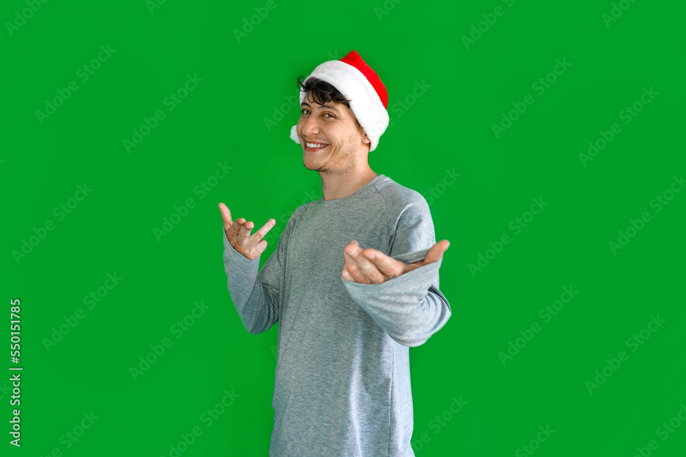 young Latino man smiling with a Christmas hat and pointing to the front with both hands. young Latino man smiling with a Christmas hat and pointing to the front with both hands.