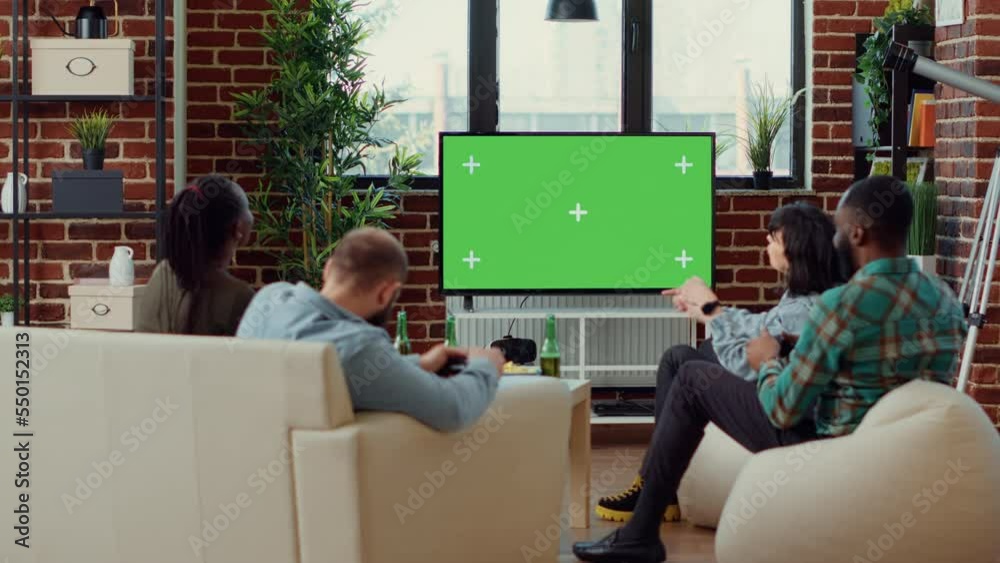 Group of people using greenscreen on tv to play video games, looking at