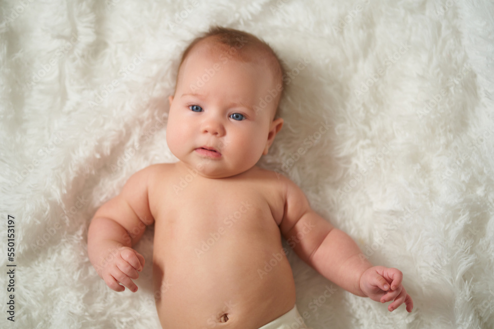 portrait of an infant lying on his back on a white comforter portrait of an infant lying on his back on a white comforter