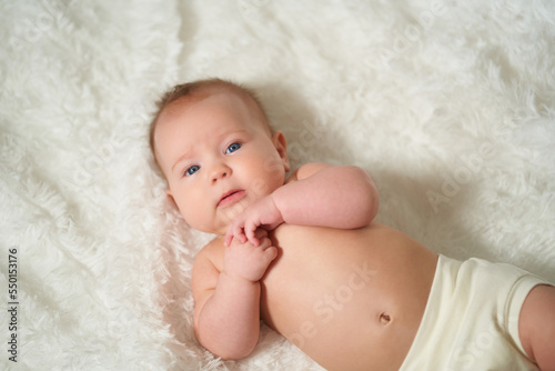 portrait of an infant lying on his back on a white comforter