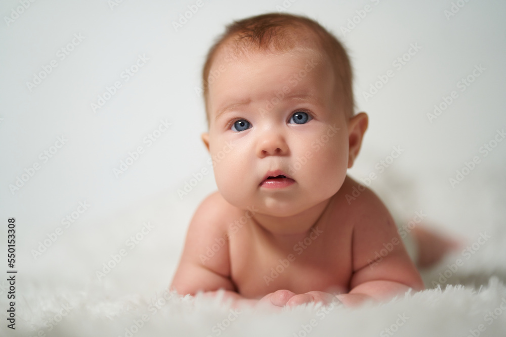 portrait of a quiet baby lying on his belly against a white background portrait of a quiet baby lying on his belly against a white background