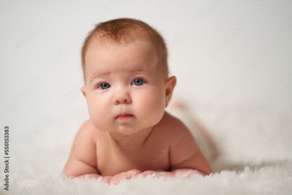 portrait of an infant with serious emotion lying on his belly against a white background portrait of an infant with serious emotion lying on his belly against a white background