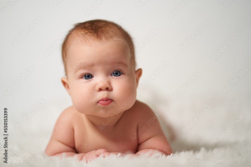 portrait of a quiet baby lying on his belly against a white background portrait of a quiet baby lying on his belly against a white background