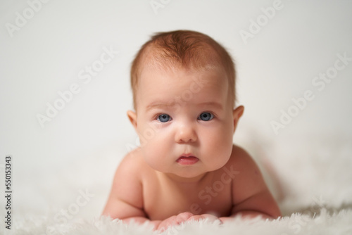 portrait of a quiet baby lying on his belly against a white background