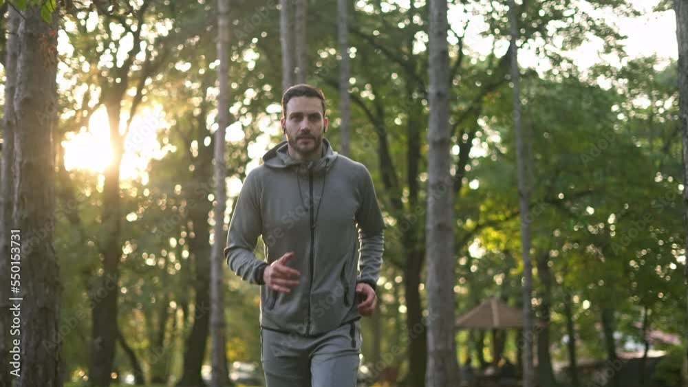 Young handsome athlete with earbuds running in the forest. Young handsome athlete with earbuds running in the forest.