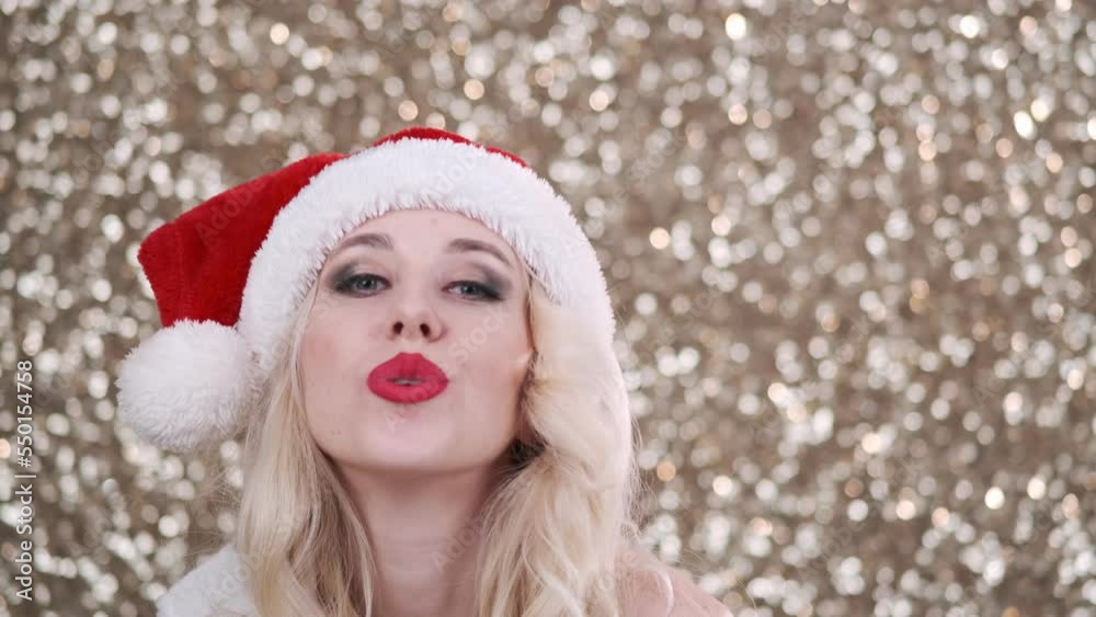 Beautiful blonde woman in a red Santa Claus outfit posing. Blows a kiss to the camera. Festive shiny golden background. Celebration of new year, christmas
Beautiful blonde woman in a red Santa Claus outfit posing. Blows a kiss to the camera. Festive shiny golden background. Celebration of new year, christmas