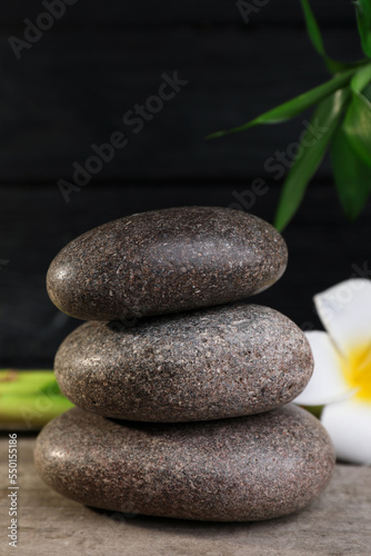 Stacked spa stones, bamboo and flower on wooden table, closeup