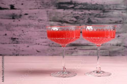 Cocktail glasses of delicious fresh watermelon juice on light wooden table. Space for text